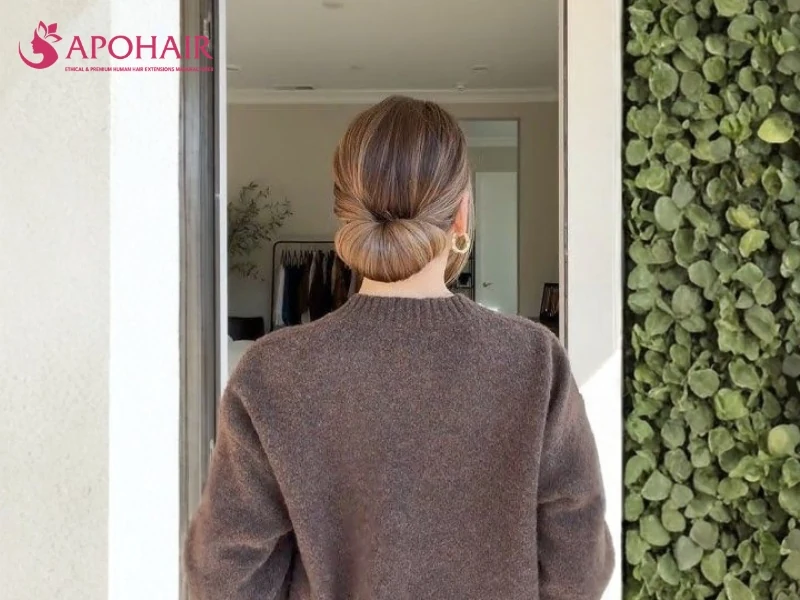 Smooth brown hair tucked into a rounded low roll at the nape